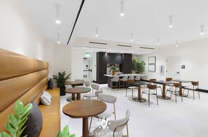 Eine moderne Hotellobby mit Sitzgelegenheiten, Tischen und einer Küche im Hintergrund.
