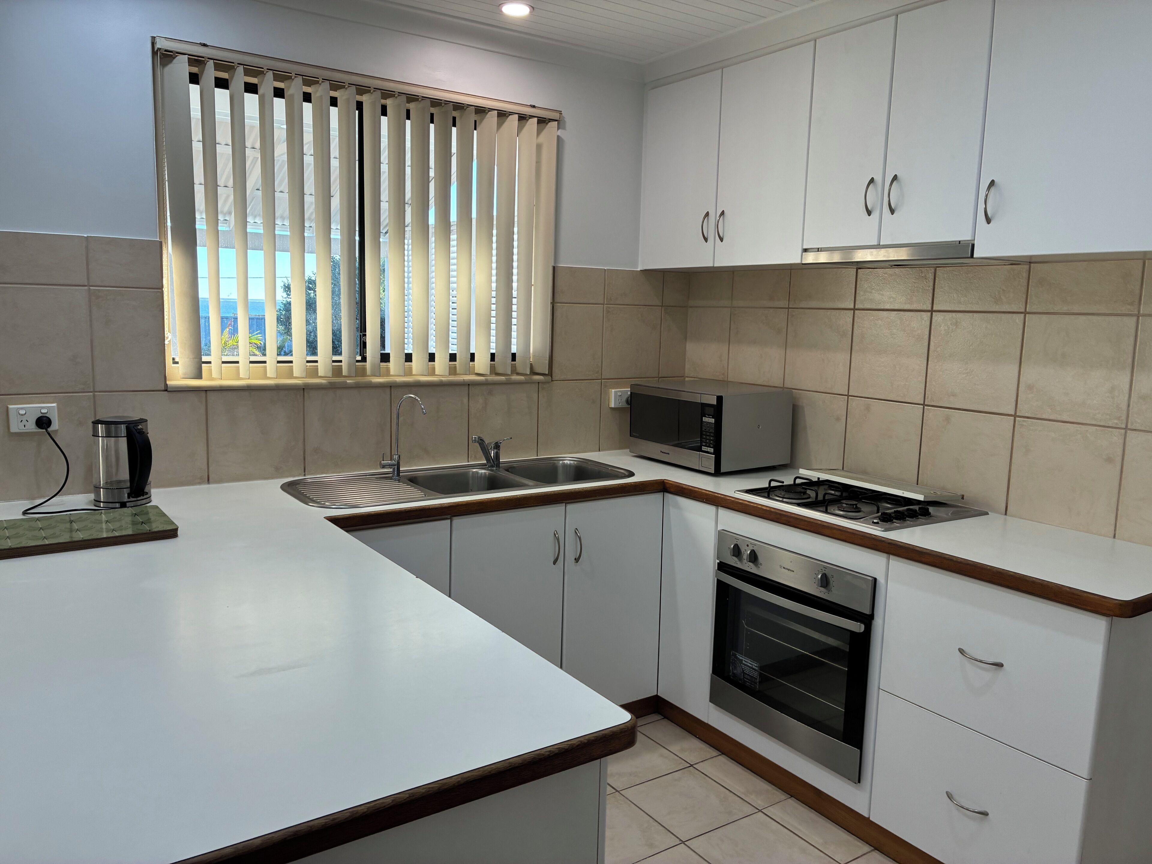 A kitchen with a sink, stove, microwave, and cabinets.