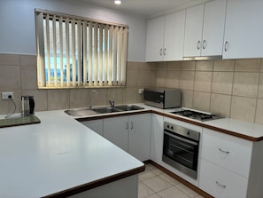 A kitchen with a sink, stove, microwave, and cabinets.