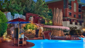 A pool area with a waterfall feature, a covered seating area, and a stone wall. - Anaheim | Romantic Disney Retreat | Pool + Spa (Anaheim)