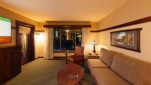 A hotel room with a sofa, armchair, and a small table with a lamp. There is a window with curtains and a view of the outside. - Anaheim | Romantic Disney Retreat | Pool + Spa (Anaheim)