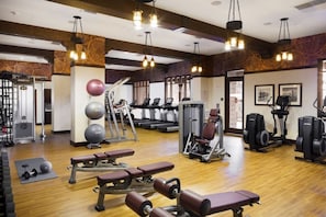 A gym with treadmills, elliptical machines, weight benches, and free weights.