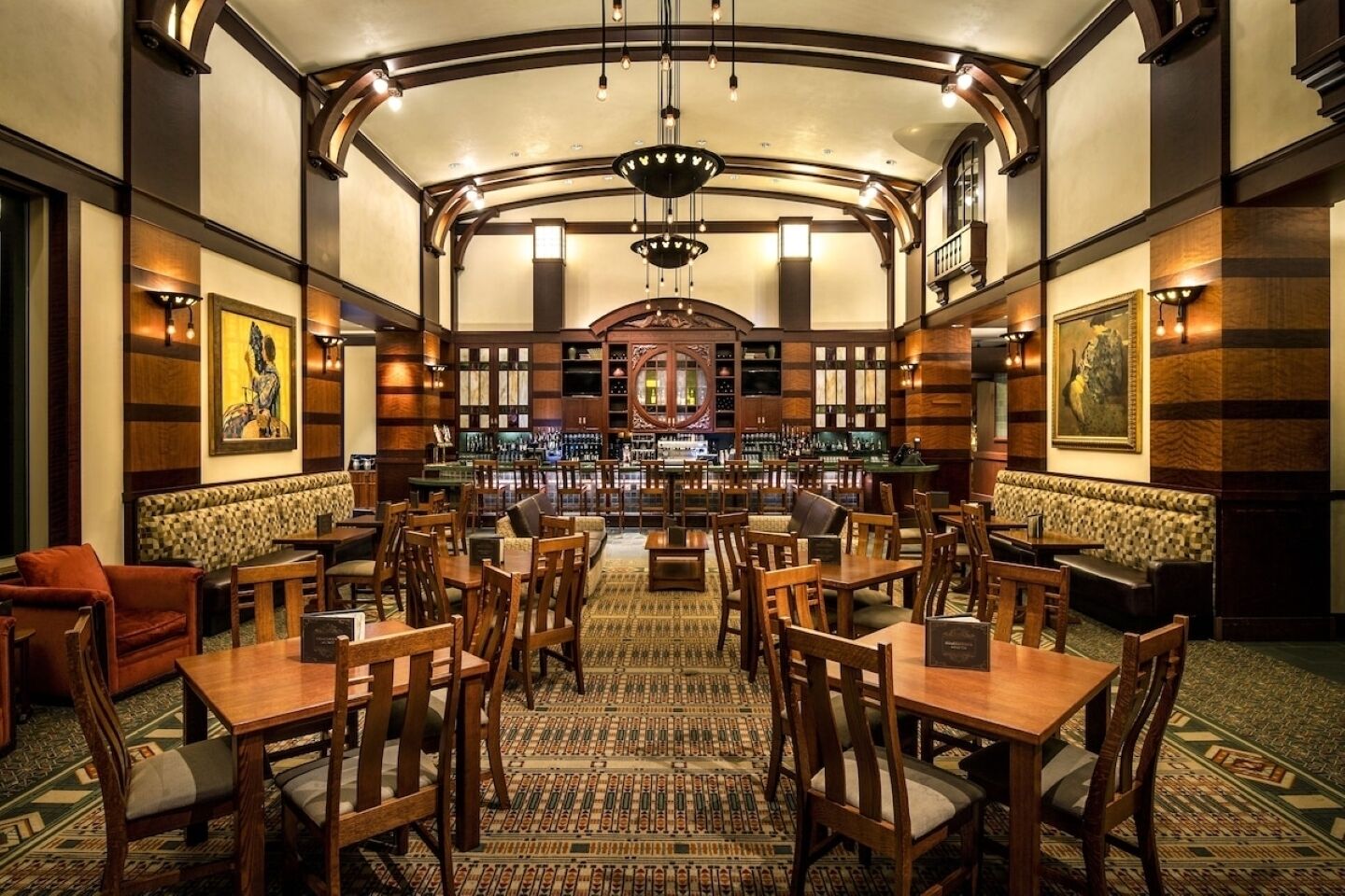 A bar area with wooden furniture, a patterned carpet, and a bar counter with bottles.