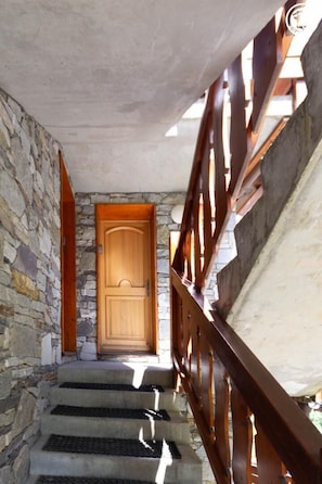 A staircase with a wooden door at the top, leading to a stone wall.