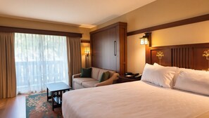 Een hotelkamer met een bed, een bank, een bureau en uitzicht op de omgeving.