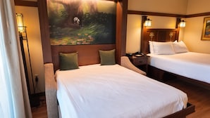 Een hotelkamer met twee bedden, een schilderij van een boom en een nachtkastje met een lamp.