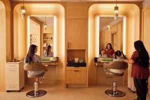 A salon with two chairs, a reception desk, and a mirror.