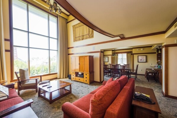 A spacious living room with a large window, a fireplace, and a dining area with multiple chairs.