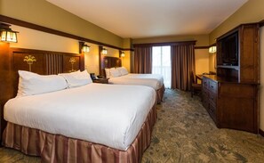 A hotel room with two beds, a TV, a desk, and a chair.