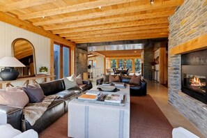 Ein geräumiges Wohnzimmer mit Kamin aus Stein, Ledersofas und einem großen Spiegel.