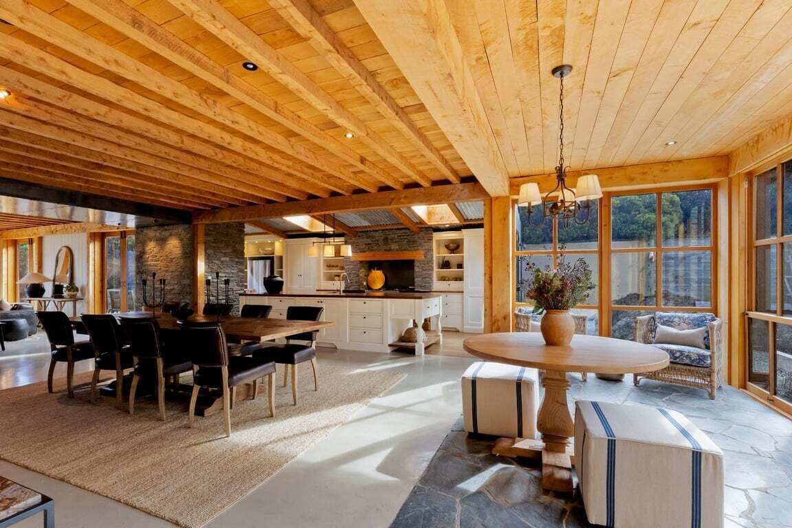 A spacious interior with a high ceiling, a dining area, kitchen, and large windows offering views.