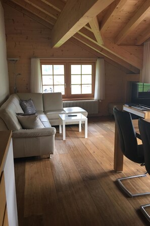 A cozy living room with a sofa, a coffee table, and a TV. - Chalet Lohner Appartement/Fewo, Bad, WC, 2 Schlafräume 3-Zimmerwohnung by Interhome (Adelboden)