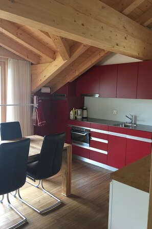 A modern kitchen with red cabinets, a stainless steel oven, and a wooden ceiling. - Chalet Lohner Appartement/Fewo, Bad, WC, 2 Schlafräume 3-Zimmerwohnung by Interhome (Adelboden)