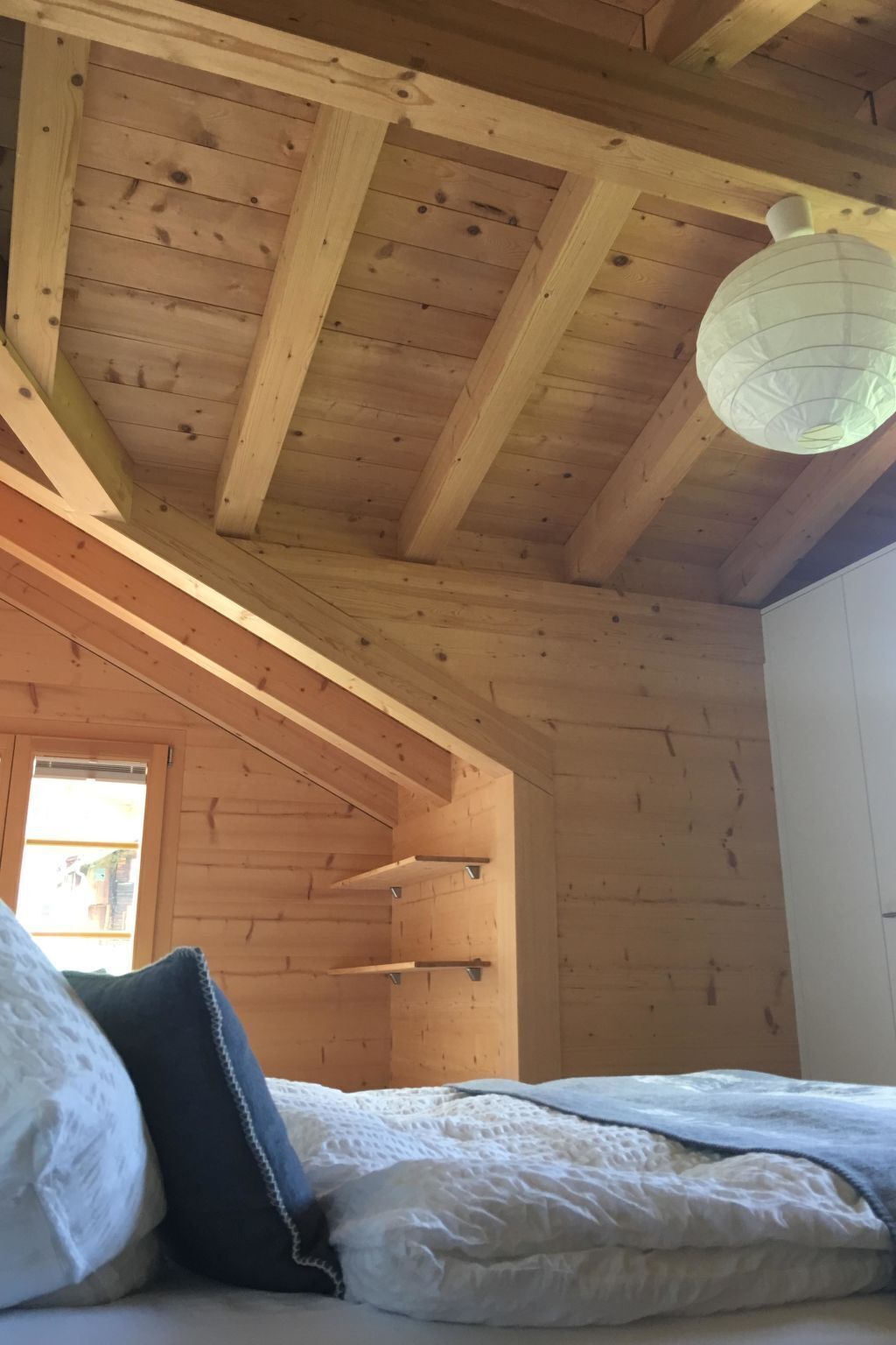 Eine Holzbalkendecke mit freiliegenden Balken und einer hängenden Leuchte.