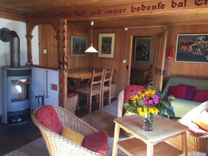 A cozy room with a wood stove, wicker furniture, and a dining table. - Sunnebühl Appartement/Fewo, Bad, WC, 3 Schlafräume Ferienhaus 5.5-Zimmerwohnung by Interhome (Adelboden)