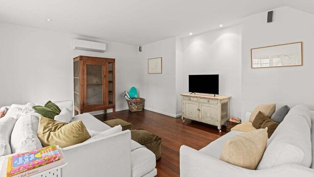 A living room with a white sofa, a wooden cabinet, a television, and a framed picture on the wall. - Willowbank Homestead (Greater Geelong)