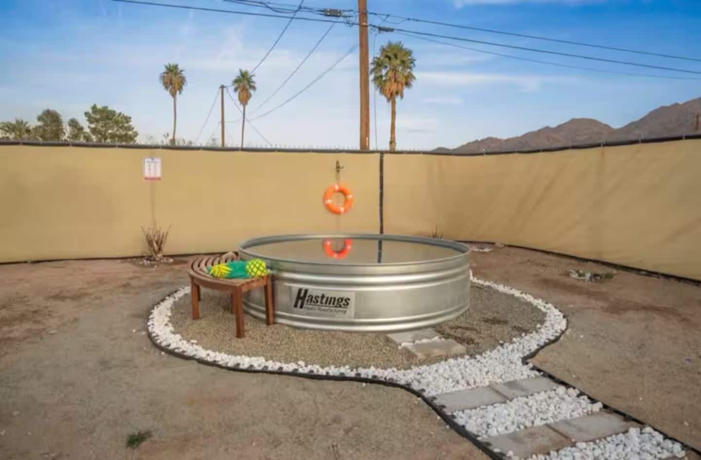 A backyard with a circular pool, a small wooden bench, and a hammock.