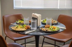 A dining table with plates of food, glasses, and a napkin center. - 2 bedroom Joshua Tree Retreat with Hot Tub + Cowboy Pool (Twentynine Palms)