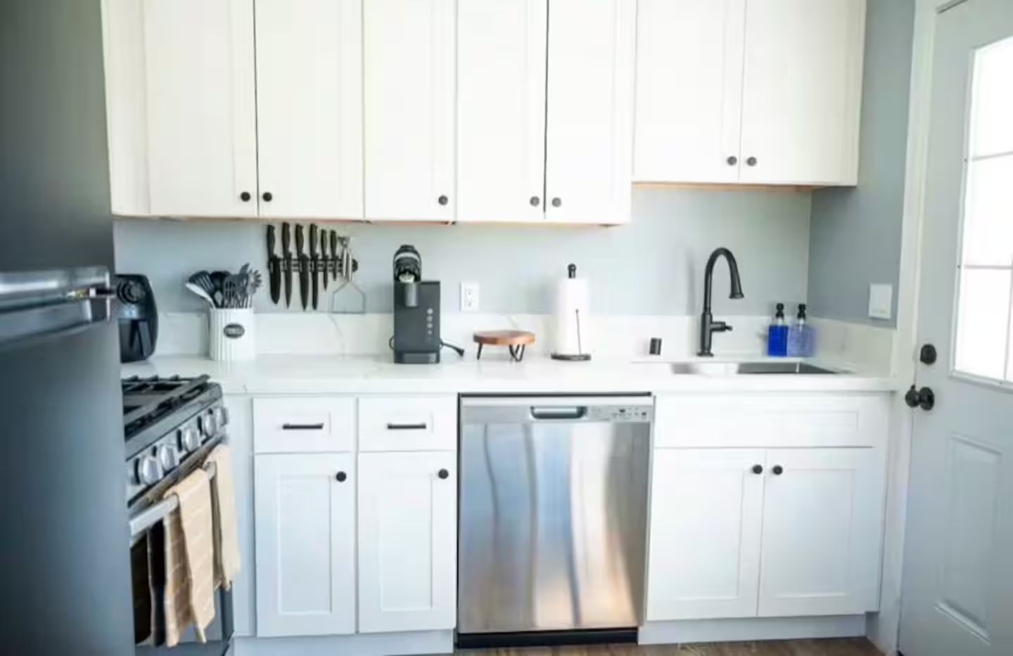 Uma cozinha moderna com armários brancos, eletrodomésticos de aço inoxidável e uma máquina de lavar louça.