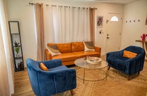 A living room with a sofa, two armchairs, a coffee table, and a door with a window. - 2 bedroom Joshua Tree Retreat with Hot Tub + Cowboy Pool (Twentynine Palms)