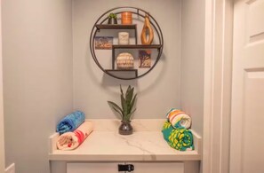 Une salle de bain avec un porte-serviettes, une plante en pot et un comptoir en marbre.