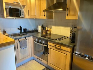 A modern kitchen with wooden cabinets, a stainless steel refrigerator, a built-in microwave, and a gas stove. - Apartment 5 People with pool in Saillagouse (Saillagouse)