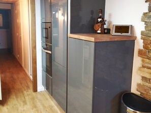 A modern kitchen with a built-in oven and a digital clock on a shelf. - Bolquère Ski Slopes Apartment (Bolquere)