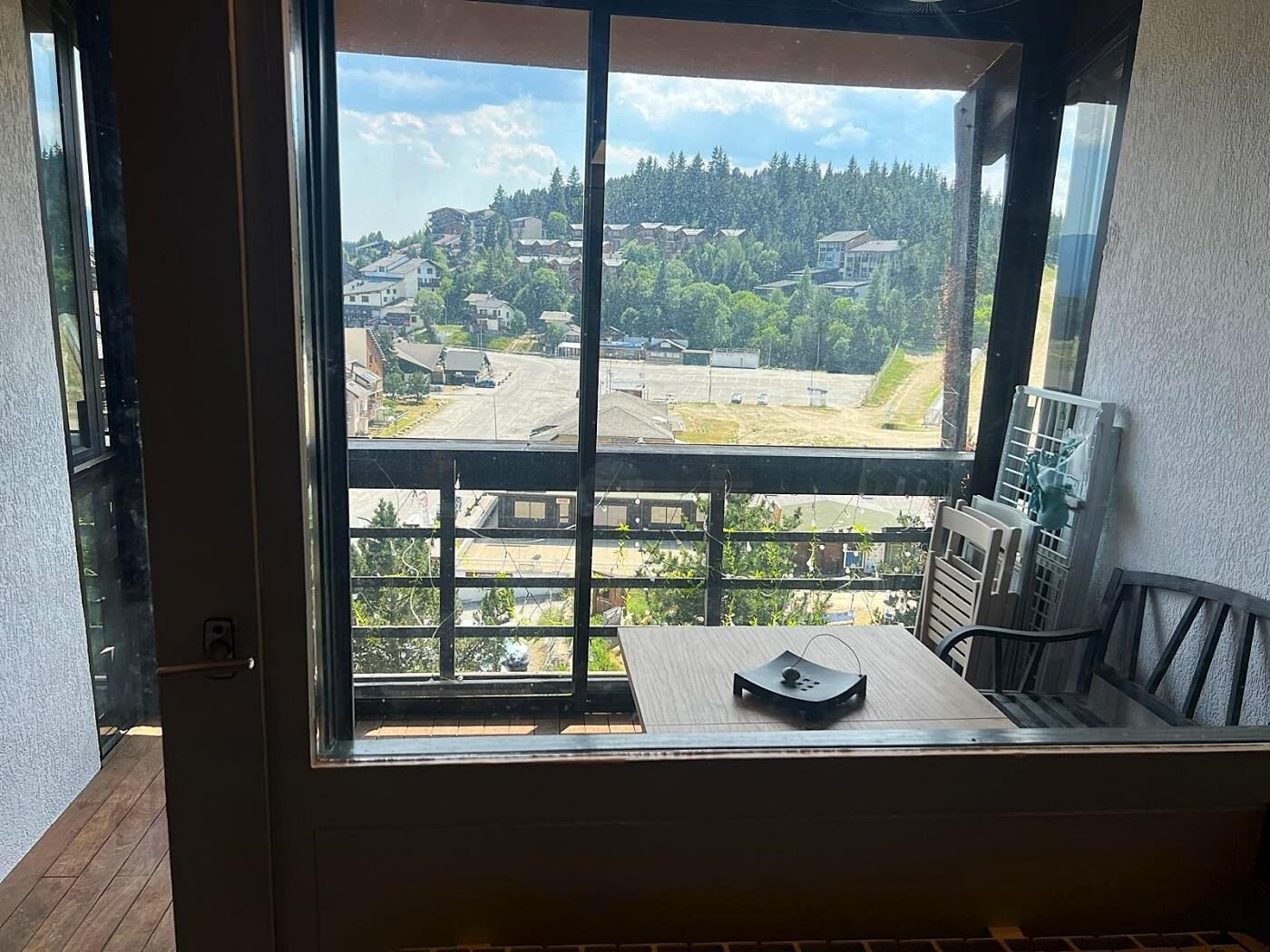 A room with a large window offering a view of a residential area with houses and trees.
