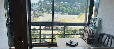 A room with a large window offering a view of a residential area with houses and trees.