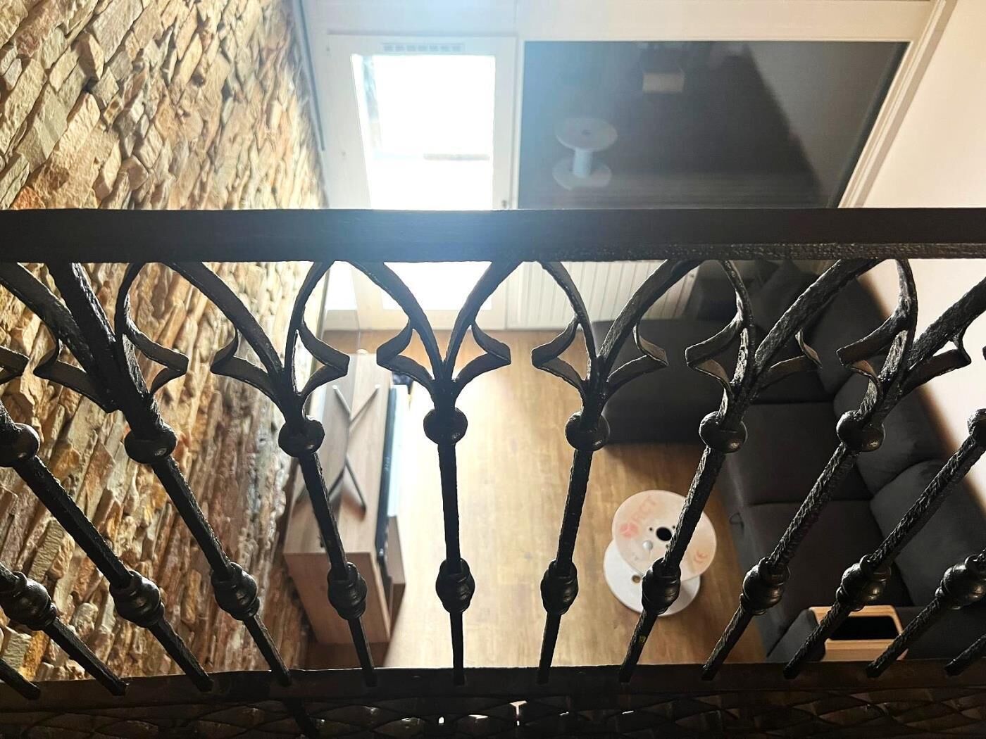 Een ijzeren poort met uitzicht op een kamer met een houten vloer, een ronde tafel en een bank.