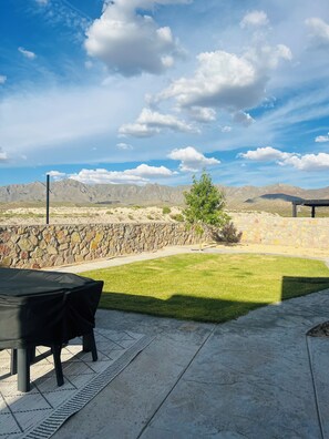 An outdoor patio with a table and chairs, a stone wall, and a view of mountains.