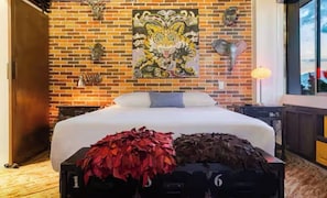 Ein Schlafzimmer mit Backsteinwand, einem Bett, einem Nachttisch, einer Lampe und einem Fenster.
