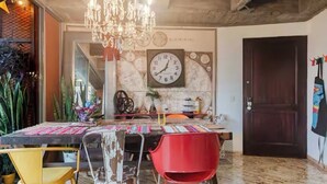 A dining area with a round table, chairs, a chandelier, and a wall clock. - Industrial DesignTerrace El Poblado fast WIFI (Medellín)
