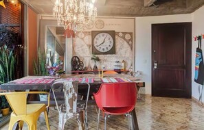 Ein Essbereich mit einem runden Tisch, Stühlen, einer Kronleuchter und einer Wanduhr.