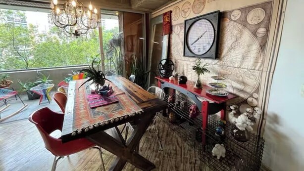 A dining area with a wooden table, red chairs, a chandelier, and a wall clock. - Industrial DesignTerrace El Poblado fast WIFI (Medellín)