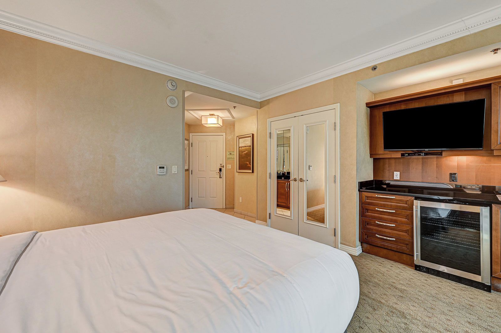 Une chambre d’hôtel avec un grand lit, une kitchenette équipée d’un four à micro-ondes et un téléviseur.