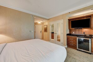 Habitación de hotel con una cama grande, una kitchenette con microondas y un televisor.