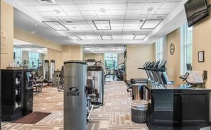 Un gimnasio con equipo de ejercicio variado, incluyendo cintas de correr y máquinas de pesas, y una máquina CYBEX.
