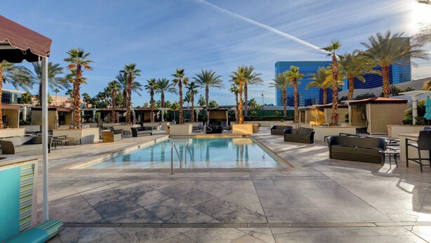 A pool area with lounge chairs and palm trees, surrounded by buildings. - Penthouse Suite MGM Signature (Las Vegas)