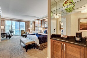 A hotel room with a large bed, a desk, a chair, a small table, and a kitchenette. - Penthouse Suite MGM Signature (Las Vegas)
