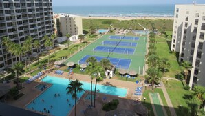 Ett semesterhotell med flera tennisbanor, en swimmingpool och utsikt över stranden.