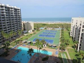 Ein Resort mit mehreren Tennisplätzen, einem Schwimmbad und Blick auf den Strand.