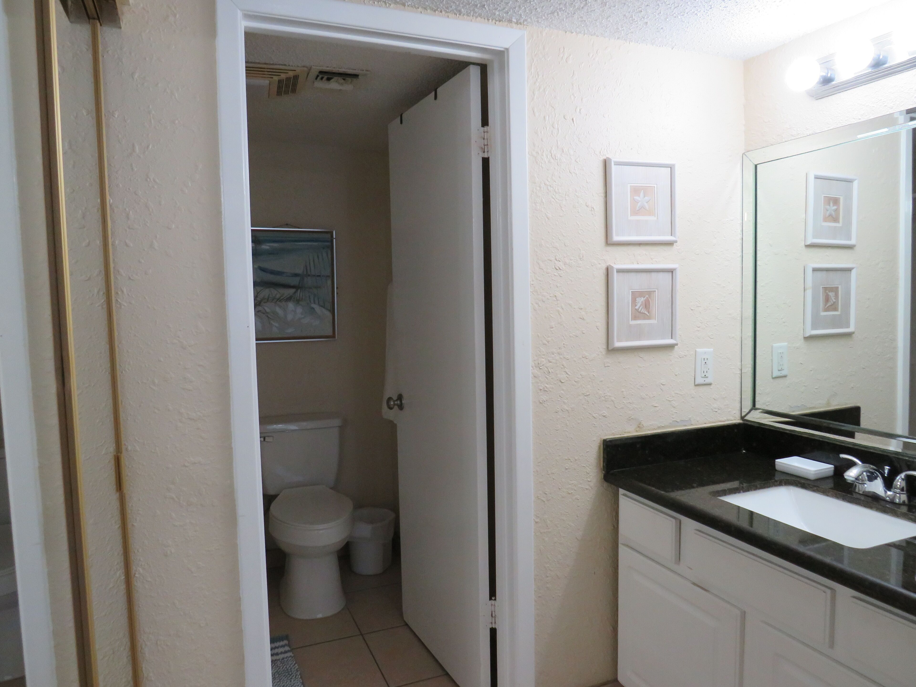 A bathroom with a toilet, sink, and a mirror.