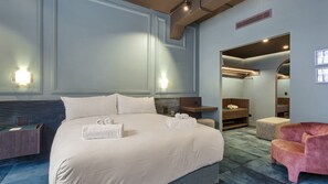 A hotel room with a large bed, bedside tables, a seating area with a chair, and a bathroom visible through an open door. - Heritage Residence Four Bedrooms Four Bathrooms (Auckland City)