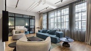 Ein modernes Wohnzimmer mit einer Couch, Sesseln, einem Couchtisch und einem Fernseher.
