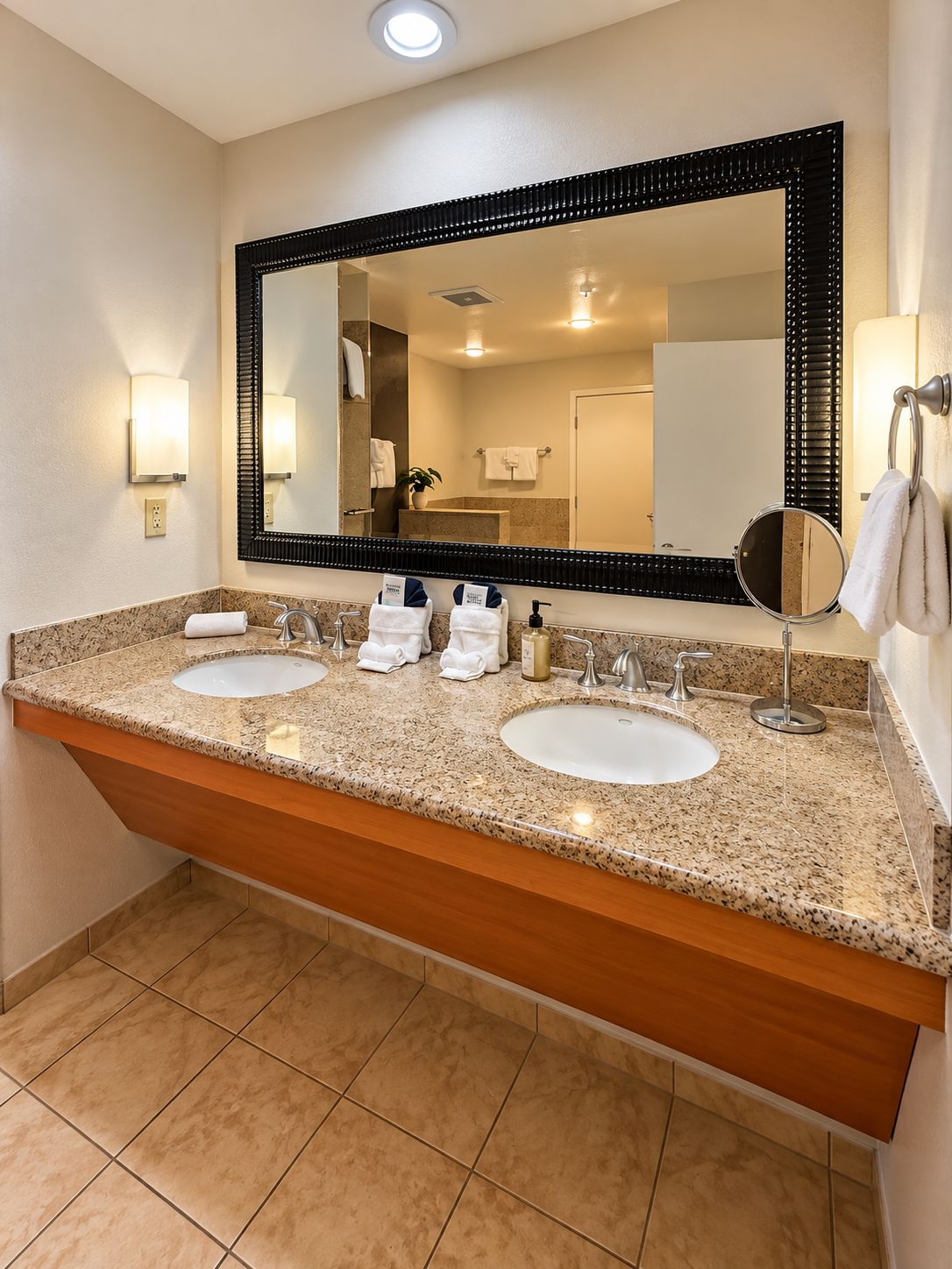 Un baño de hotel con dos lavamanos, un espejo grande y un perchero para toallas.