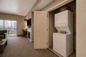 A compact living space with a kitchenette, a flat-screen TV, a dining area, and a view of the city.