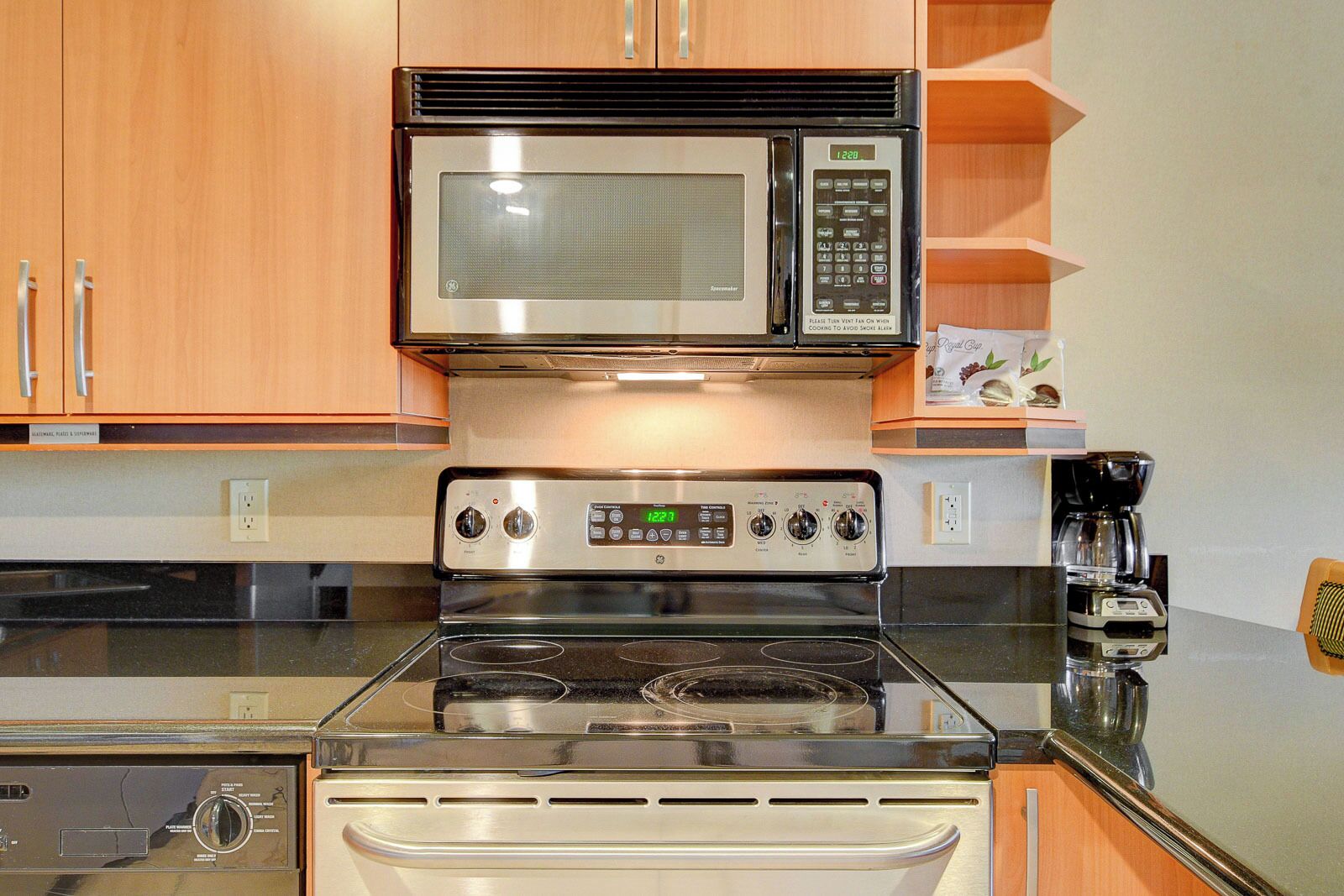 A kitchen with a stainless steel stove, microwave, and coffee maker.