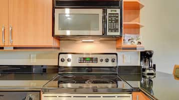 A kitchen with a stainless steel stove, microwave, and coffee maker.