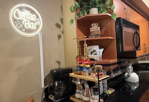 A kitchen with a coffee bar sign, a coffee maker, a microwave, and various coffee-related items. - Executive Suite Balcony Platinum Hotel (Las Vegas)